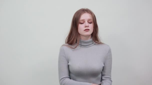 Молодая красивая рыжая женщина в сером свитере мягко закрывает глаза — стоковое видео