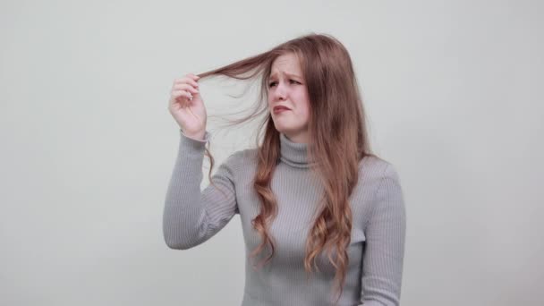 Rödhårig kvinna i grått tittar på skört hår med förtvivlan, ånger frustration — Stockvideo