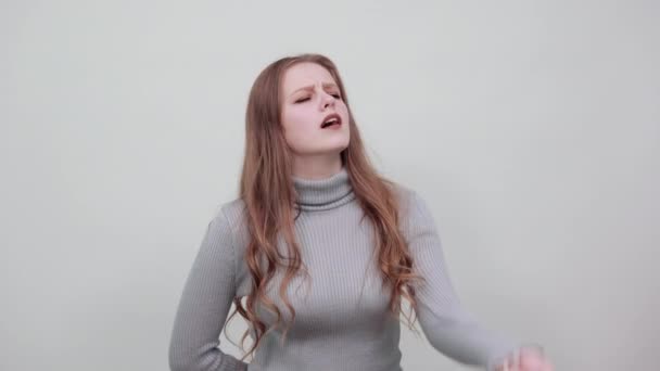 Red-haired woman in a gray sweater shows a gesture of surprise and pretension — Stock Video