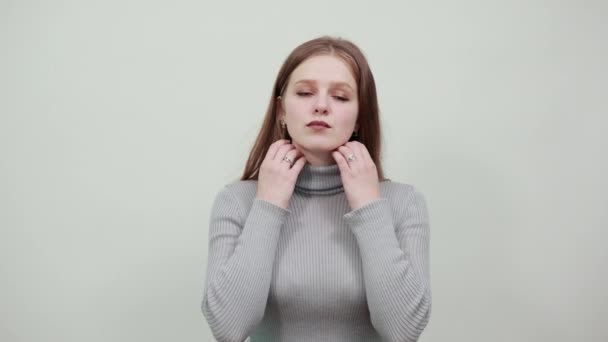 Vrouw houdt haar kraag met beide handen en is ontevreden met uitdrukking op gezicht — Stockvideo