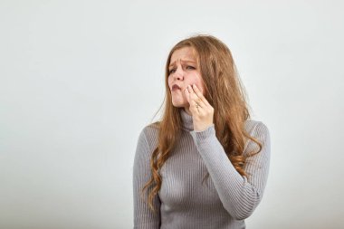 Gri kazaklı kadın diş ağrısından muzdarip diş ağrısı el ele tutuşmasına neden oluyor.