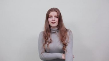 Gri kazaklı güzel kızıl saçlı kadın üç parmağını göstermekten mutlu.