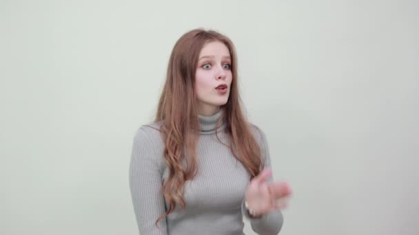 Vrouw in grijs trui is geschokt door nieuws raakt hand tot wang opent mond — Stockvideo