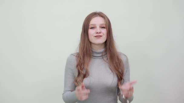 Kvinna i grå tröja är glad gör hål i kinderna med pekfingrar, ler — Stockvideo