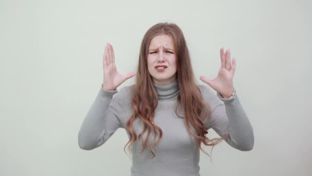 Mujer en suéter gris reacciona irritablemente, una expresión enojada en la cara agitando las manos — Vídeo de stock