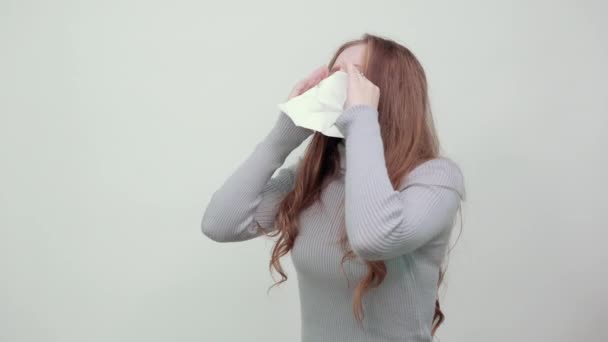 Gyönyörű vörös hajú nő szürke pulóverben törli az orrát zsebkendővel — Stock videók