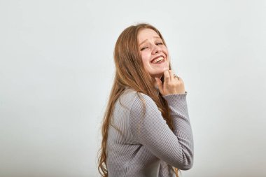 Gri kazaklı kadın gülümsüyor çenesini eliyle tutuyor ve gülümsüyor