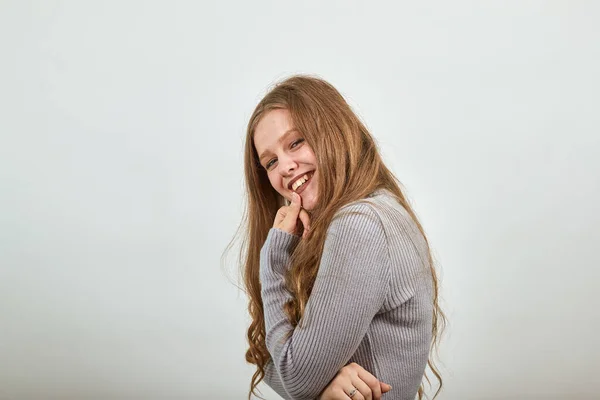 Vrouw in grijs trui is gebogen over en glimlachend verlegen houden kin in haar hand — Stockfoto