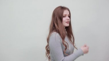 Gri kazaklı kadın gülümsüyor çenesini eliyle tutuyor ve gülümsüyor