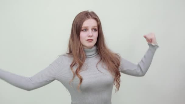 Женщина в сером показывает свои мышцы на руках, демонстрируя силу уверенности — стоковое видео