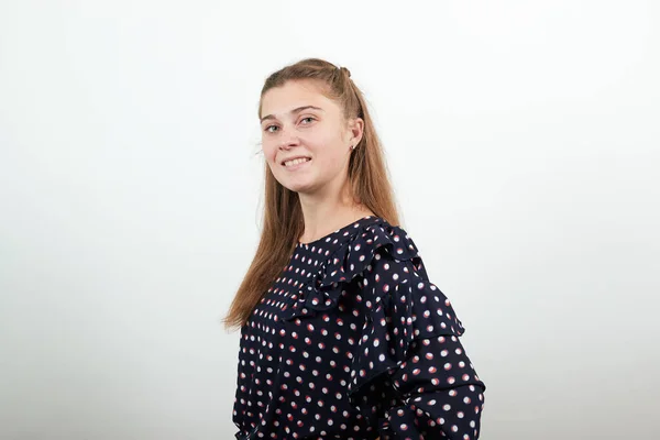 Fair-haired girl in black dress with white circles stands looking straight ahead — Stock Photo, Image