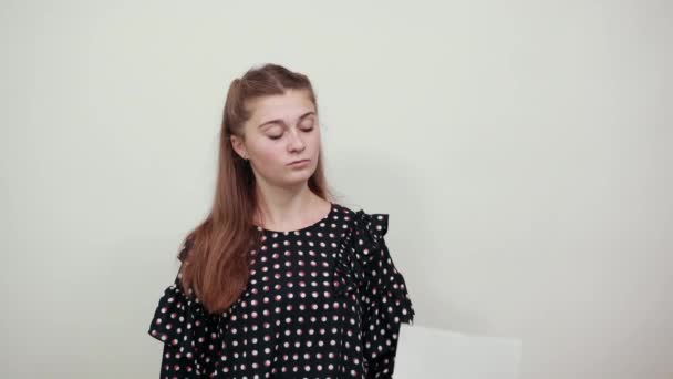 Fair-haired girl in black dress with white circles shows blank paper in surprise — ストック動画