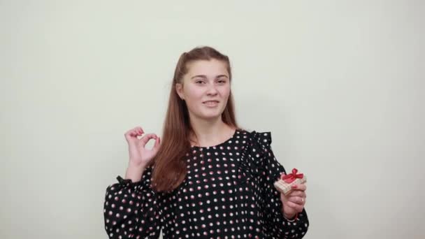 Hermosa chica de pelo rubio en un vestido negro con círculos blancos muestra un signo OK — Vídeo de stock