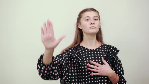 Menina em um vestido preto com círculos brancos sorri e mostra parar de assinar sua palma — Vídeo de Stock