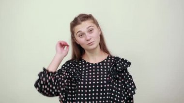 Beyaz halkalı siyah elbiseli kız elleriyle saçlarını düzeltiyor.