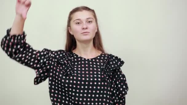 Дівчина в чорній сукні з білими колами кладе великі пальці вниз з поганим настроєм — стокове відео