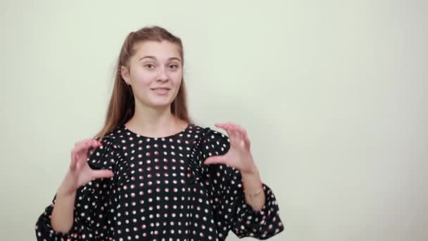 Girl in a black dress makes heart shape with her hands and smiles happily — Stok video