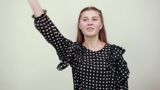 Chica en un vestido negro con círculos blancos habla mientras sostiene su mano a cara — Vídeo de stock