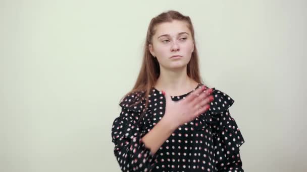 Girl in a black dress with white circles holds her hands around neck — Stok video