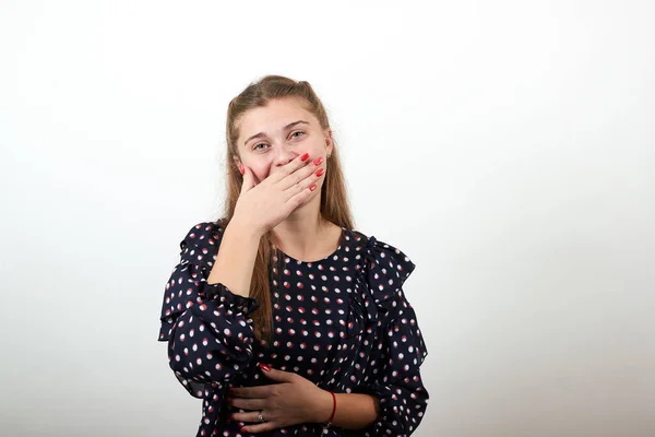 Fille dans une robe noire avec des cercles blancs couvert sa bouche avec la main souriante — Photo