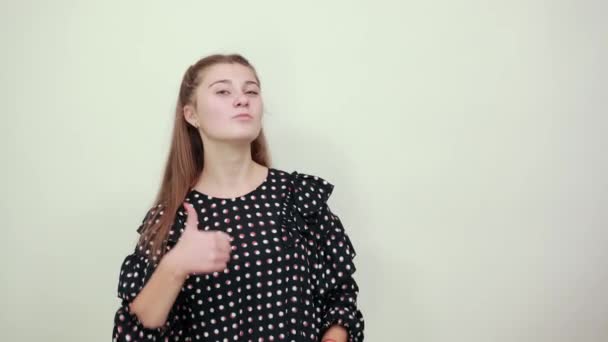 Lány egy fekete ruha fehér körökben boldog nő feladja hüvelykujját az öröm — Stock videók