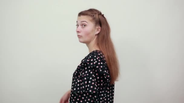 Chica en un vestido negro sorprendido confundido muestra la dirección de la mano por detrás — Vídeos de Stock