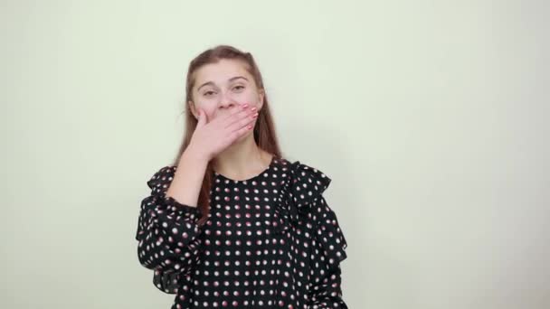 Дівчина в чорній сукні з білими колами прикрила рот посмішкою руки — стокове відео