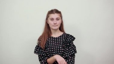 Siyah elbiseli kız rüya gibi görünüyor. Parmağını çenesinde tutuyor.