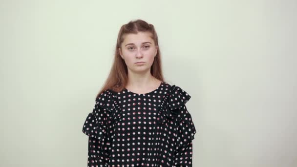 Chica en vestido con círculos blancos irritablemente cruzó las manos y se ve nerviosa — Vídeos de Stock