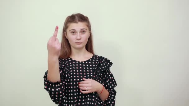 Девушка в черном платье с белыми кругами показывает средний палец сердитый негативный — стоковое видео