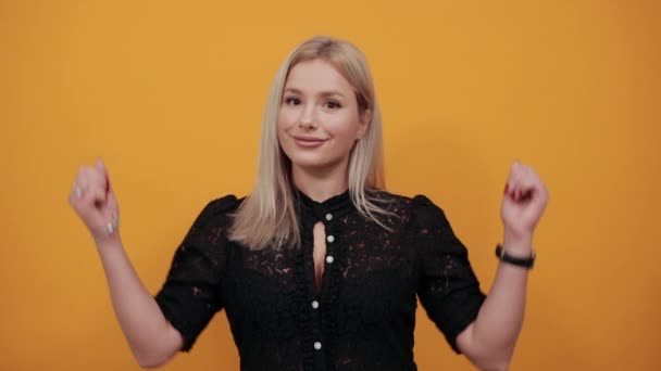 Chica en vestido negro sobre fondo amarillo mujer feliz apareció y muestra las palmas — Vídeos de Stock