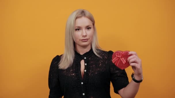 Chica en vestido negro mujer sorprendida es feliz con el regalo en rojo en forma de corazón — Vídeos de Stock