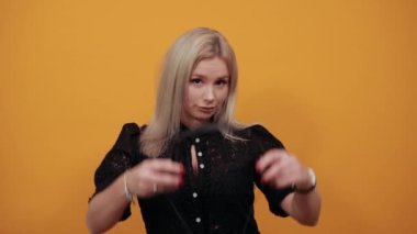 Sarı arka planda siyah elbiseli kız kulaklıkla dans eden şık kadın.