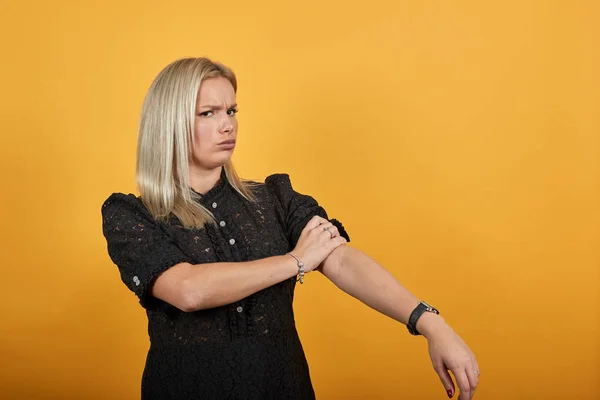 Chica en vestido negro sobre fondo amarillo determinada mujer rollos hasta sus mangas —  Fotos de Stock