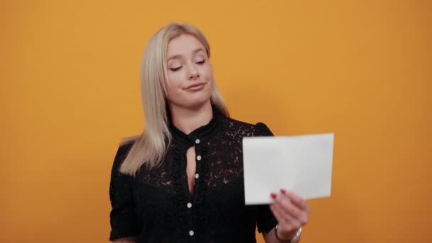 Chica en vestido negro mujer feliz sosteniendo hoja blanca de papel y sonriendo — Vídeos de Stock