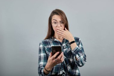 shocked woman with glasses is talking on phone that looks like an iPhone