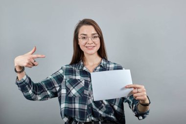 happy woman with glasses holds an empty white sheet of paper in hand