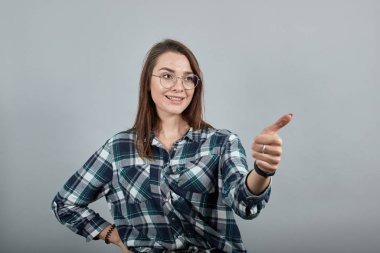 happy woman with glasses smiles and gives thumbs up, sign that everything is OK