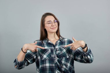 happy woman with glasses points at herself with index fingers