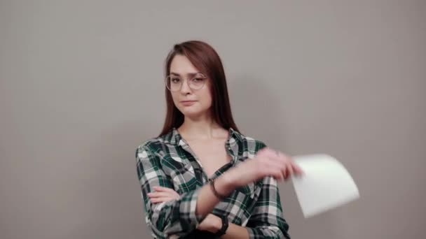 Ображена жінка в окулярах показує білий аркуш паперу — стокове відео