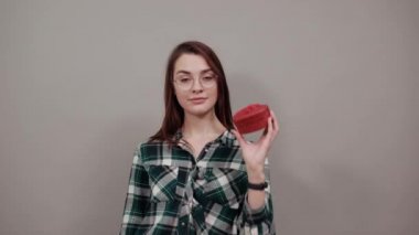happy woman with glasses holds gift box in form of a red heart in her hand