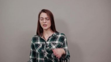 on grey background upset woman tilted her head, has bad mood