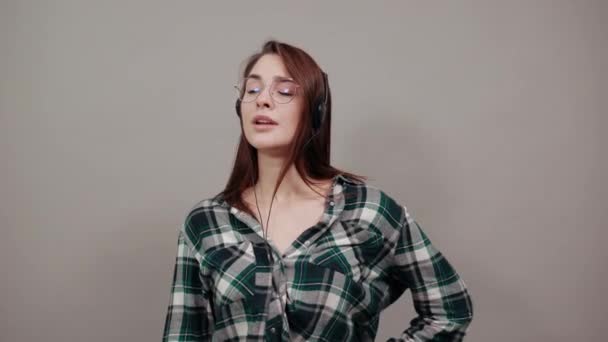 Happy woman listens to music on headphones, gestures with hand in displeasure — Stok video