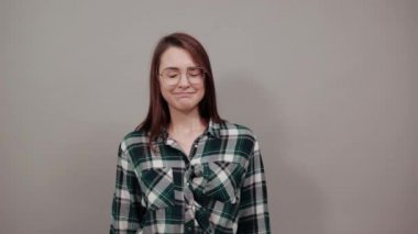 on grey background upset woman in glasses with bad mood