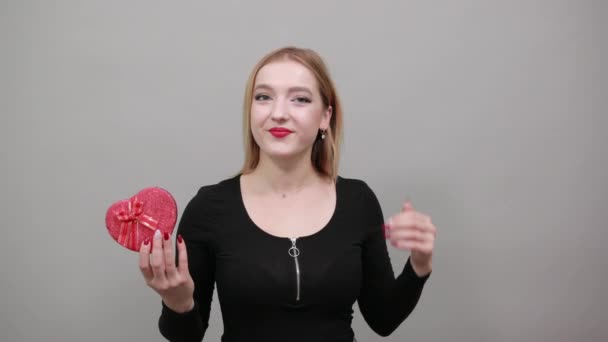 Gelukkig vrouw houden een rood hart-vormige geschenkdoos in haar hand, palm omhoog — Stockvideo
