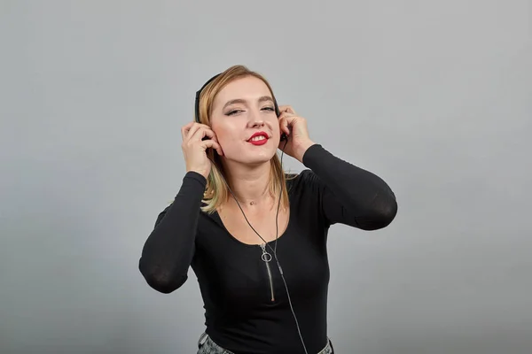 Lány fekete kabát boldog nő hallgat zenét fejhallgatóval és mosolygós — Stock Fotó