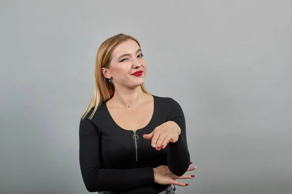 Siyah ceketli genç sarışın kadın kendi elleriyle gösteriş yapıyor.
