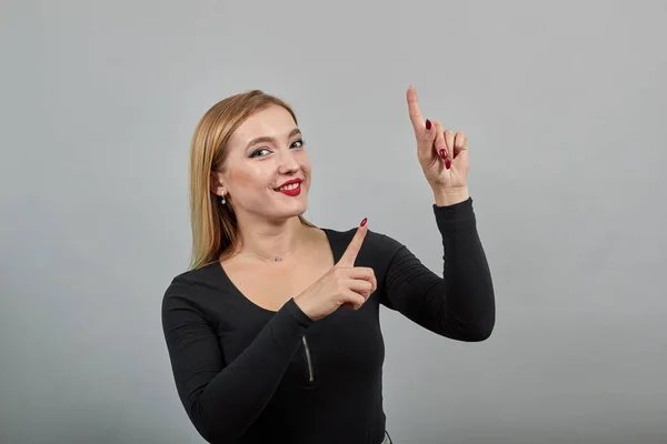 Junge Blondine in schwarzer Jacke glücklich Frau zeigt Zeigefinger nach oben — Stockfoto