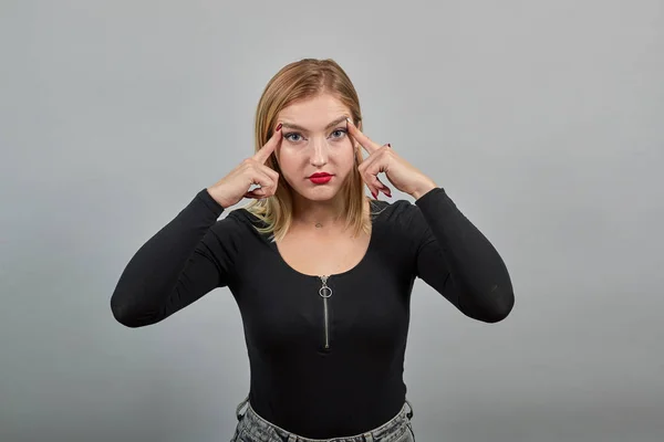 Ernsthafte Frau denkt, ein Problem lösen zu können, hält ihre Zeigefinger in Kopfnähe — Stockfoto
