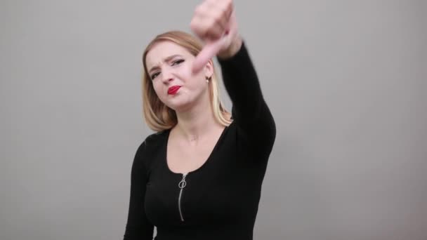 黒のジャケットを着た金髪の女の子が親指を立てて反対し — ストック動画